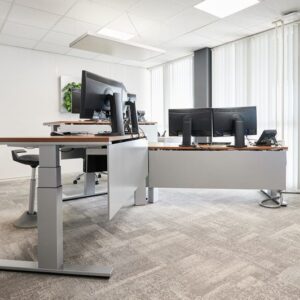 Dubbele werkplekopstelling met zit-sta bureaus en monitorarmen – ergonomische projectinrichting gericht op dynamisch werken.